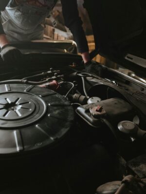 Close-up of a mechanic repairing a car engine in a garage setting.
